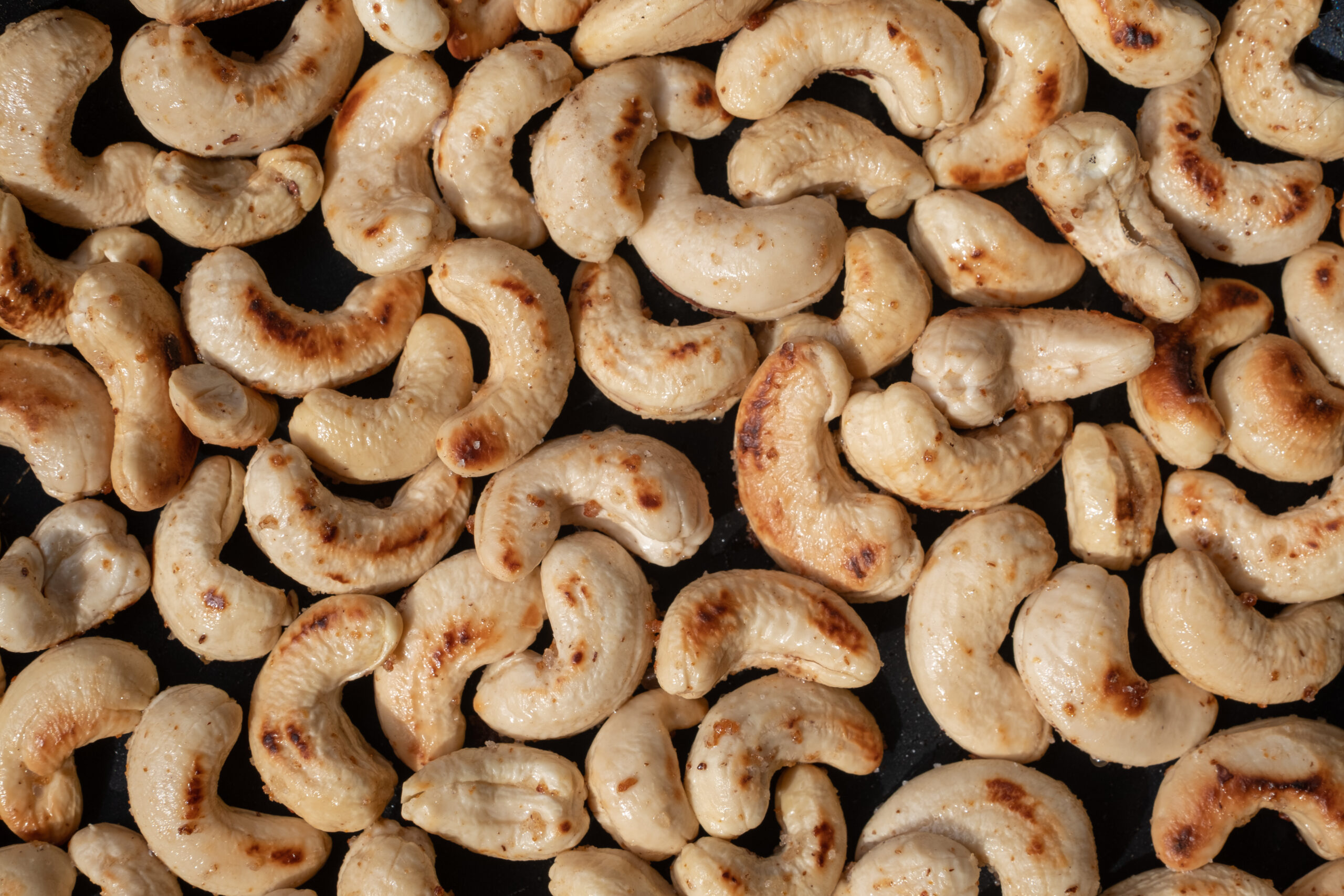 close up roasted cashew nuts and salt in a pan.concept health.