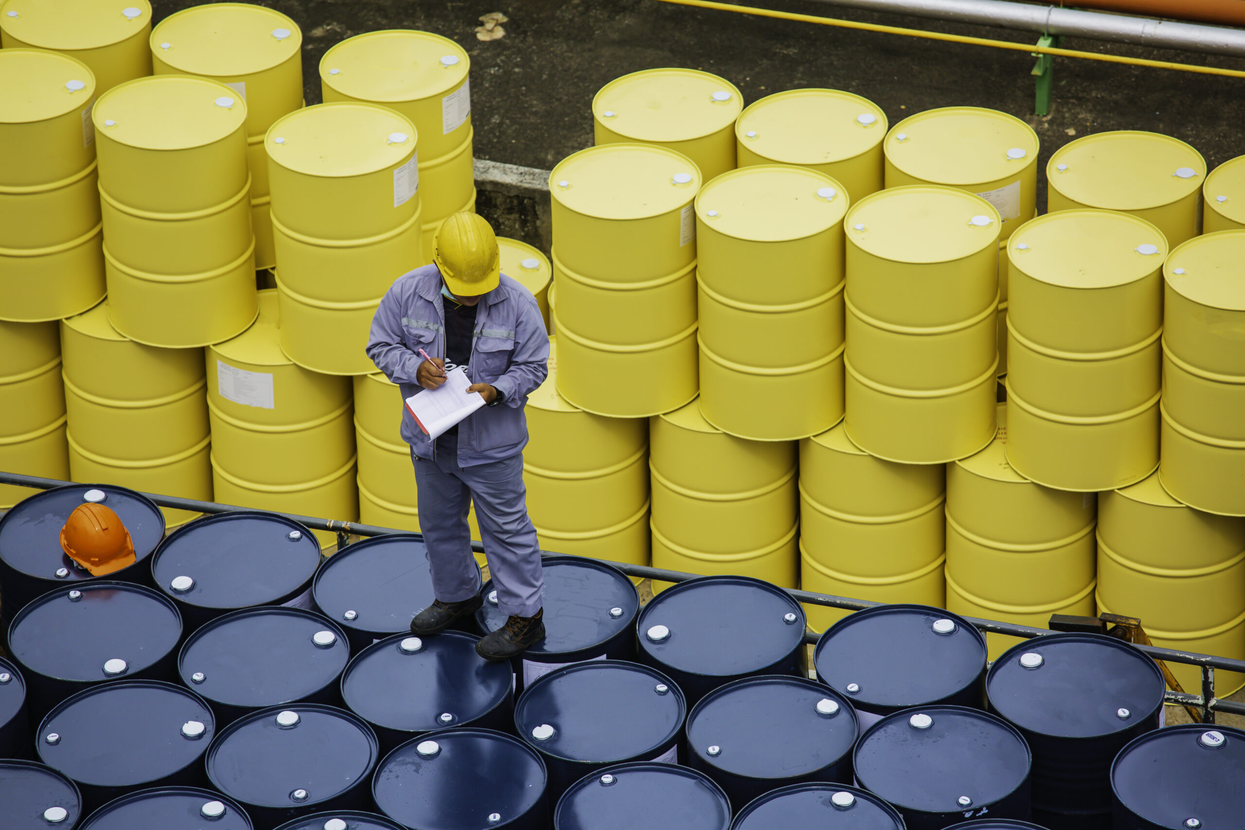 male worker inspection record drum oil stock barrels yellow vert