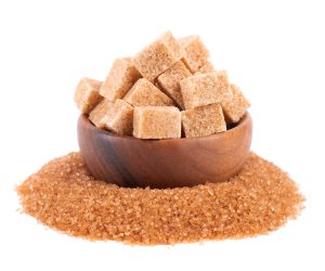 brown sugar in wooden bowl, isolated on white background. heap of cane sugar crystals and sugar cubes.