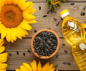 sunflower oil, seed and sunflower on grey wooden background